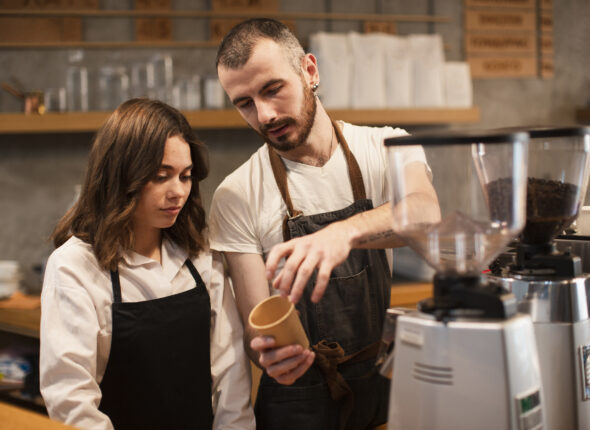 man-showing-woman-cup-with-coffee-machine